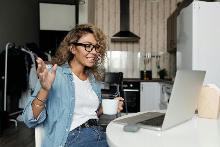 woman working on laptop with coffee in her hand